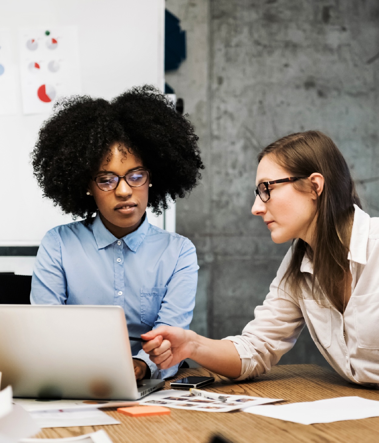 Two women going over a project on a laptop during a business meeting.