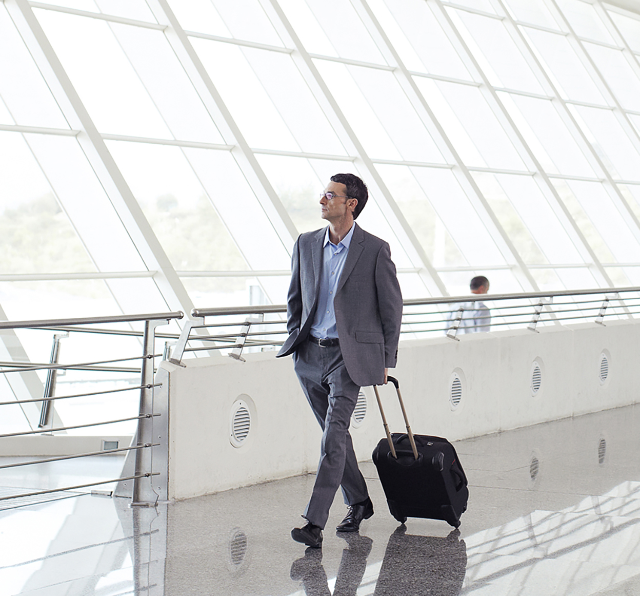Businessman walking through airport with roller luggage